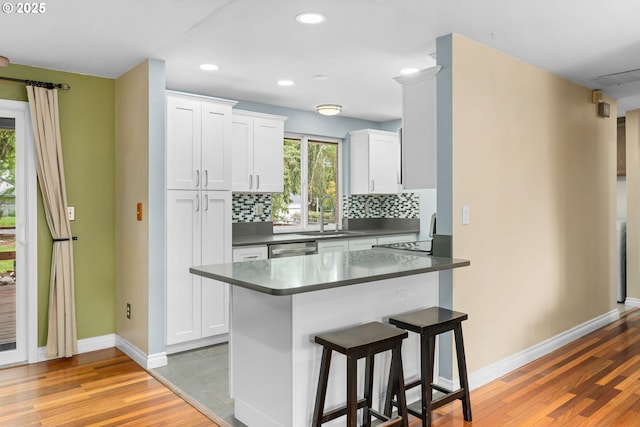 17954 NW Andria Ave, Portland, OR 97229 - kitchen featuring a sink, a kitchen bar, baseboards, dark countertops, and recessed lighting