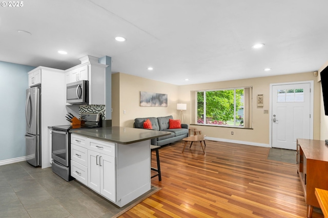 17954 NW Andria Ave, Portland, OR 97229 - kitchen featuring stainless steel appliances, open floor plan, dark countertops, white cabinets, and a kitchen breakfast bar