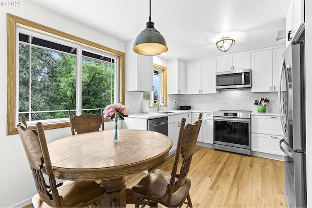 767 SW 8th St, Gresham, OR 97080 - kitchen featuring stainless steel appliances, white cabinets, decorative backsplash, and light wood-style flooring