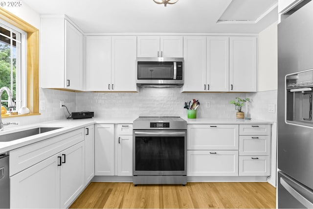 767 SW 8th St, Gresham, OR 97080 - kitchen featuring appliances with stainless steel finishes, a sink, white cabinets, and light wood finished floors