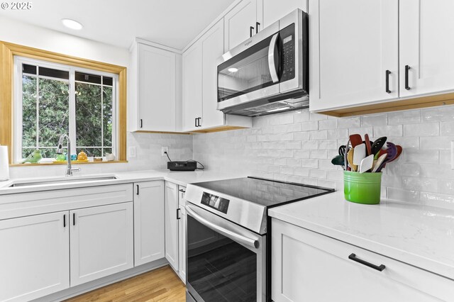 767 SW 8th St, Gresham, OR 97080 - kitchen with stainless steel appliances, a sink, light countertops, white cabinets, and decorative backsplash