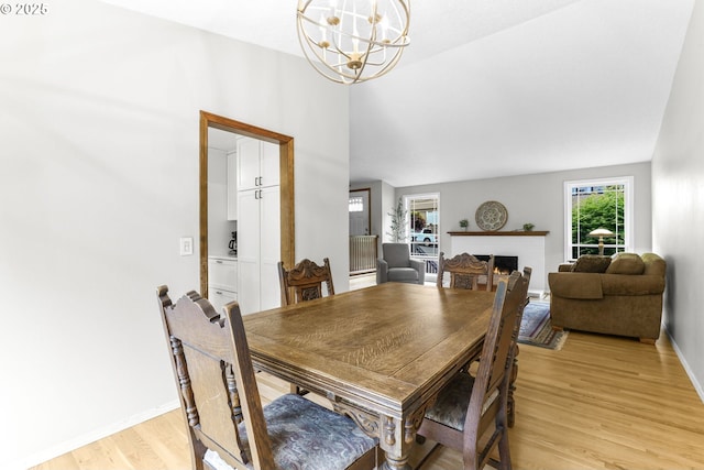 767 SW 8th St, Gresham, OR 97080 - dining space featuring a chandelier, light wood-type flooring, a warm lit fireplace, baseboards, and lofted ceiling