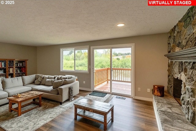 12190 SW Merestone Ct, Tigard, OR 97223 - living room featuring a textured ceiling, healthy amount of natural light, wood finished floors, and a stone fireplace