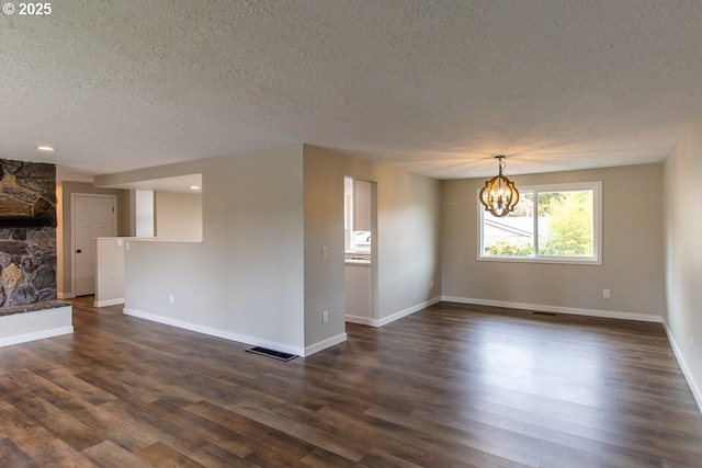 12190 SW Merestone Ct, Tigard, OR 97223 - unfurnished living room featuring a textured ceiling, a chandelier, a fireplace, dark wood-type flooring, and baseboards