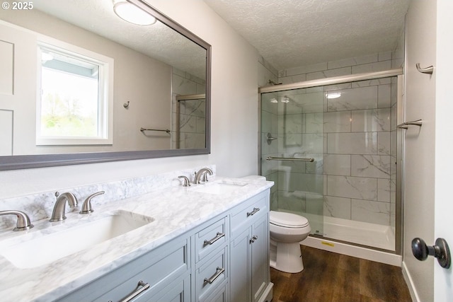 12190 SW Merestone Ct, Tigard, OR 97223 - full bathroom with toilet, a textured ceiling, wood finished floors, a stall shower, and double vanity