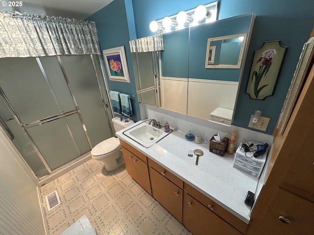 bathroom featuring vanity, toilet, and a shower with door