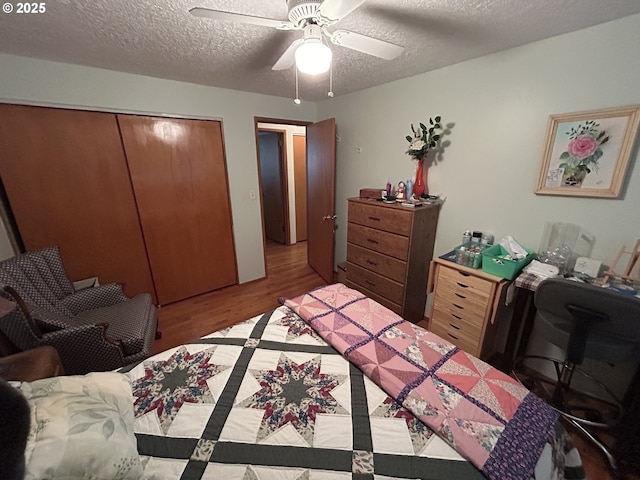 bedroom with ceiling fan, hardwood / wood-style floors, a textured ceiling, and a closet