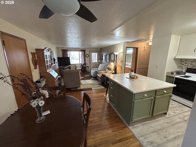 kitchen with a kitchen island, electric range oven, ceiling fan, green cabinetry, and light wood-type flooring