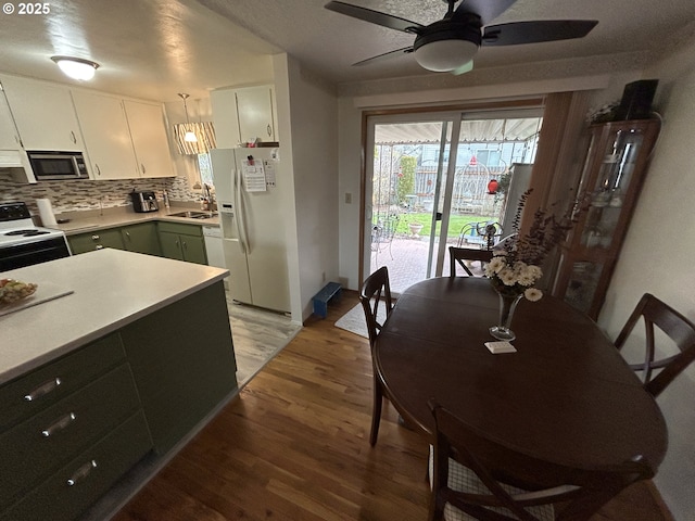 kitchen with hanging light fixtures, hardwood / wood-style flooring, electric stove, white refrigerator with ice dispenser, and white cabinets