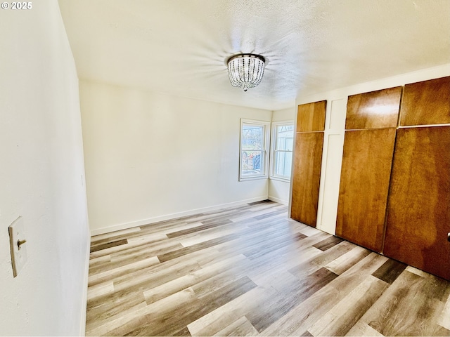 551 NW T St, Winston, OR 97496 - unfurnished bedroom with a notable chandelier, light wood-style flooring, baseboards, and multiple closets
