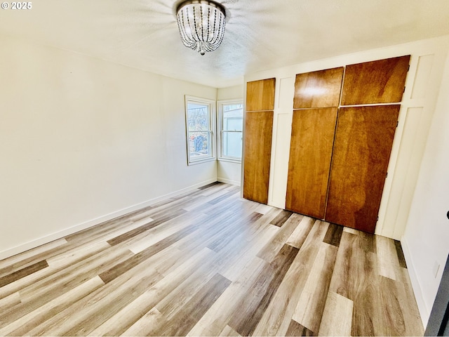 551 NW T St, Winston, OR 97496 - unfurnished bedroom featuring a chandelier, light wood finished floors, two closets, and baseboards