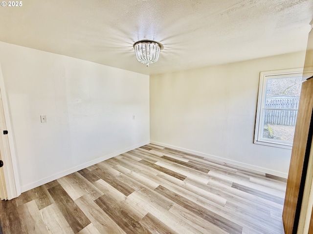 551 NW T St, Winston, OR 97496 - unfurnished room featuring a notable chandelier, light wood-style floors, baseboards, and a textured ceiling
