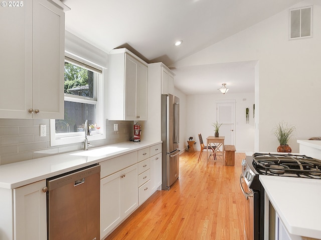1720 Kilkenny Dr, Lake Oswego, OR 97034 - kitchen with appliances with stainless steel finishes, backsplash, lofted ceiling, white cabinetry, and light wood-type flooring
