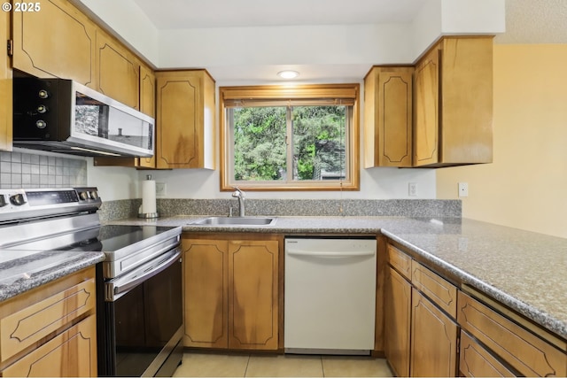4621 SW Caldew St Unit D, Portland, OR 97219 - kitchen featuring stainless steel appliances, light tile patterned flooring, and brown cabinetry
