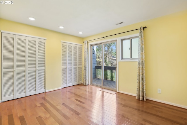 4621 SW Caldew St Unit D, Portland, OR 97219 - unfurnished bedroom featuring access to outside, wood finished floors, two closets, and recessed lighting