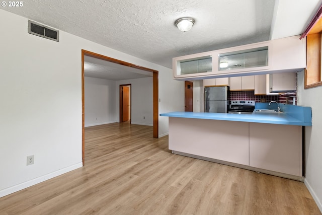 3602 NE 134th Ave, Portland, OR 97230 - kitchen with appliances with stainless steel finishes, light wood finished floors, a peninsula, backsplash, and a textured ceiling