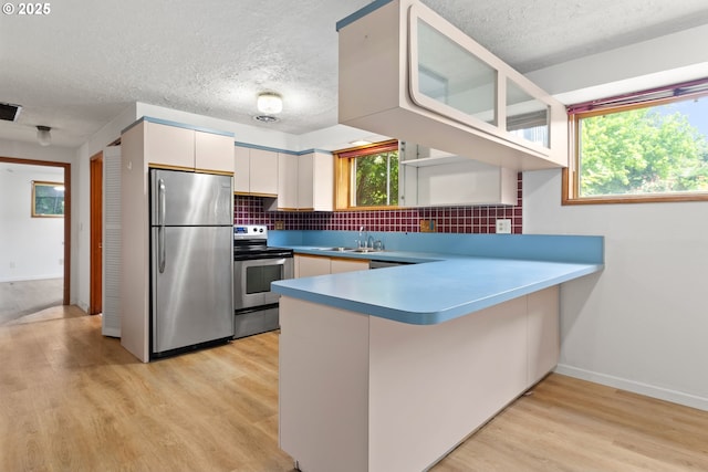 3602 NE 134th Ave, Portland, OR 97230 - kitchen featuring stainless steel appliances, white cabinetry, decorative backsplash, a peninsula, and a textured ceiling