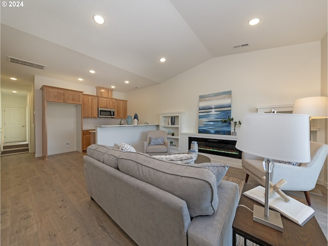 2366 Kingwood St, Forest Grove, OR 97116 - living room featuring lofted ceiling, light wood finished floors, a glass covered fireplace, and visible vents