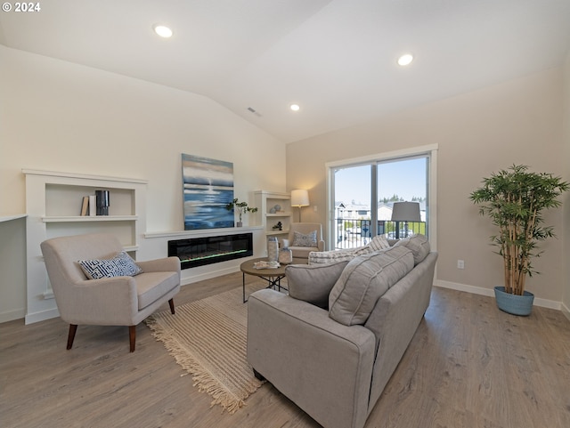 living room featuring recessed lighting, a glass covered fireplace, vaulted ceiling, wood finished floors, and baseboards