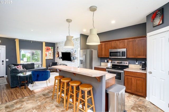 976 E 15th St, Lafayette, OR 97127 - kitchen with appliances with stainless steel finishes, open floor plan, light countertops, a breakfast bar, and brown cabinets
