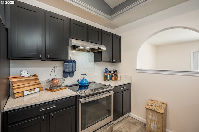 kitchen featuring stainless steel range with electric stovetop, dark cabinetry, under cabinet range hood, and light stone counters