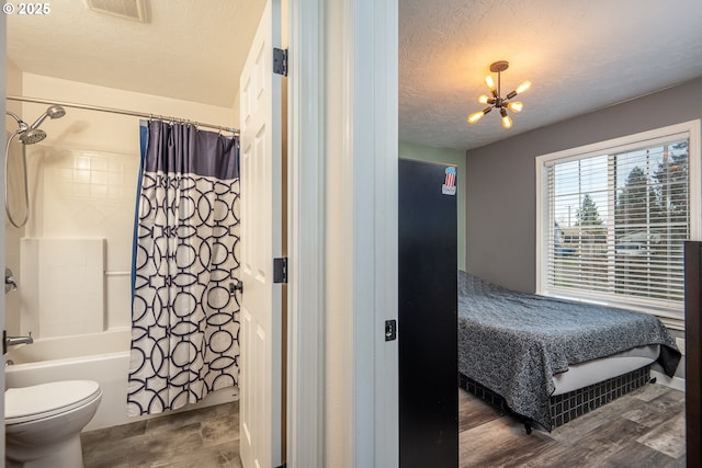 bedroom with wood finished floors, a textured ceiling, a chandelier, and visible vents