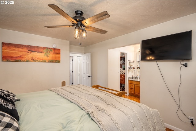 bedroom featuring a bar, light wood-type flooring, a ceiling fan, and a textured ceiling