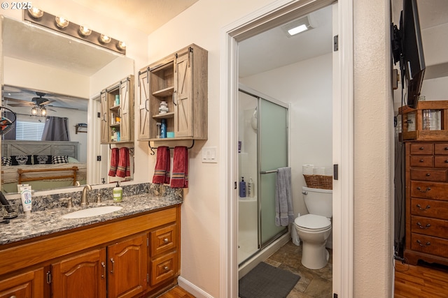 bathroom with a stall shower, toilet, ceiling fan, and vanity