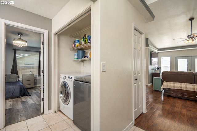 clothes washing area featuring light wood finished floors, washer and clothes dryer, a healthy amount of sunlight, and laundry area