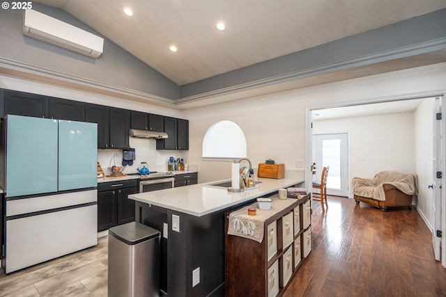 kitchen featuring a wall mounted air conditioner, wood finished floors, under cabinet range hood, a breakfast bar area, and freestanding refrigerator