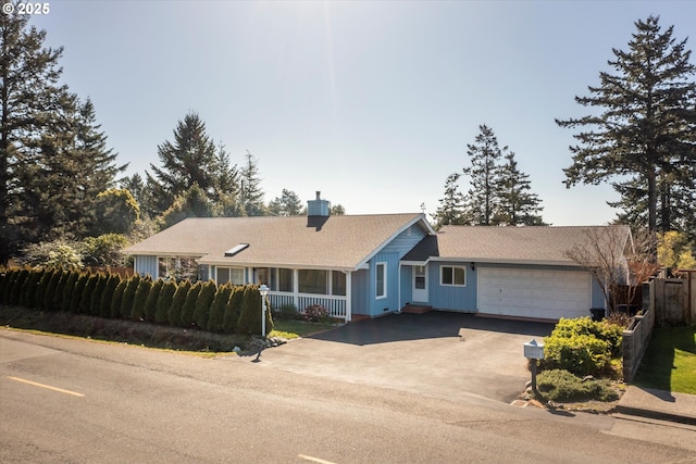 single story home featuring fence, covered porch, a garage, aphalt driveway, and board and batten siding