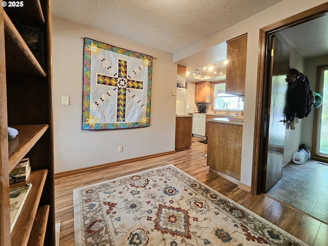 288 N Dorcas Dr, Keizer, OR 97303 - kitchen featuring light wood-style floors, dishwasher, a textured ceiling, light countertops, and brown cabinets