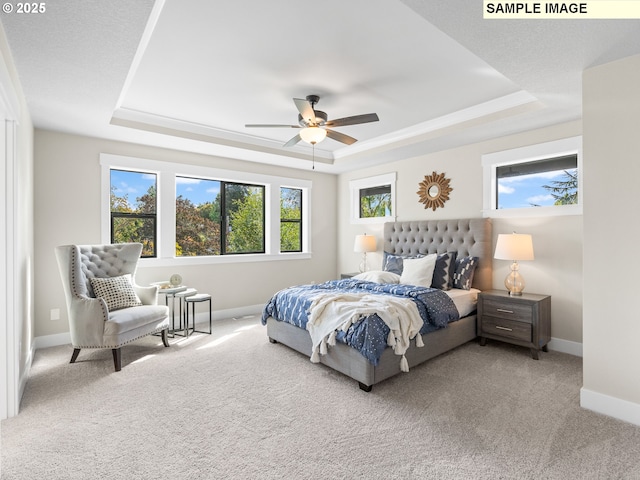 carpeted bedroom featuring ceiling fan and a tray ceiling