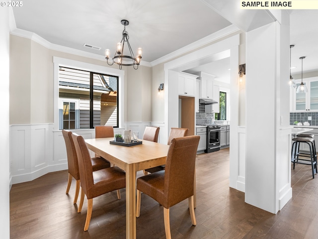 dining room featuring dark hardwood / wood-style flooring, crown molding, and a notable chandelier