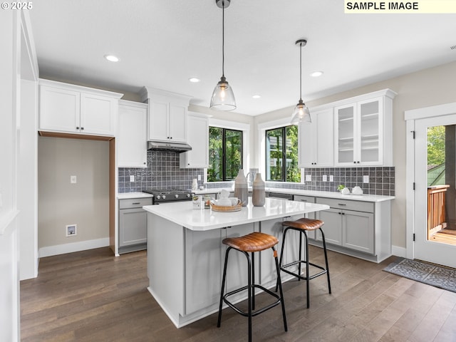 kitchen with a kitchen breakfast bar, a kitchen island, white cabinetry, and hanging light fixtures