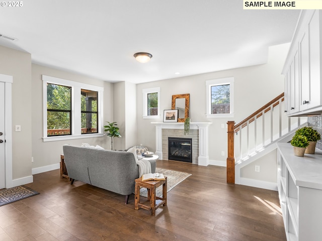 living room featuring a tile fireplace and dark wood-type flooring