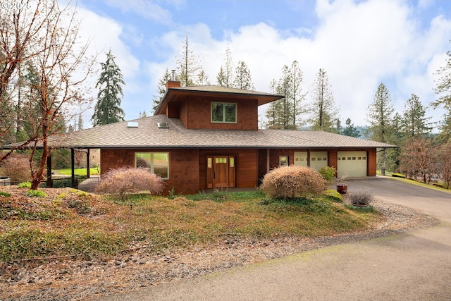 prairie-style house featuring aphalt driveway, an attached garage, and a chimney