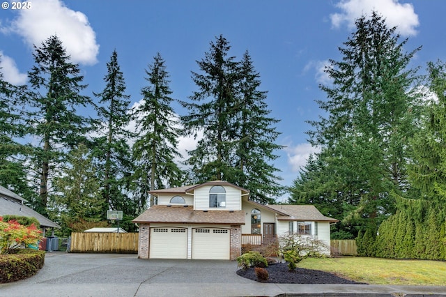 split level home featuring a garage, brick siding, driveway, and fence