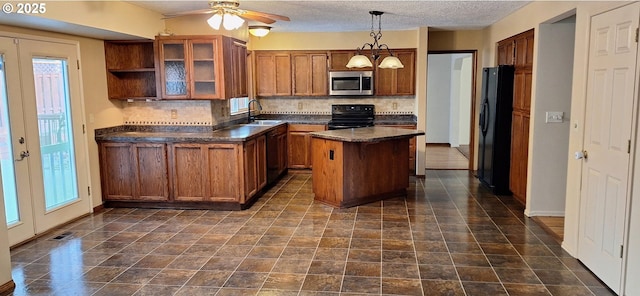 kitchen with dark countertops, glass insert cabinets, hanging light fixtures, black appliances, and a sink