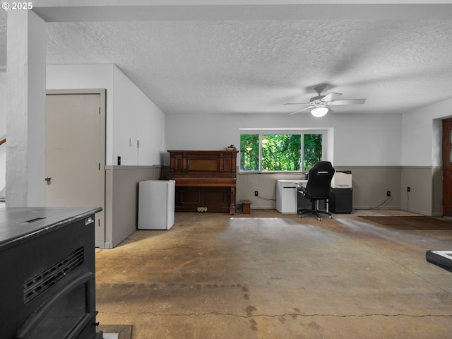 17222 SE Tickle Creek Rd, Boring, OR 97009 - office area featuring unfinished concrete floors, a wood stove, a ceiling fan, and a textured ceiling
