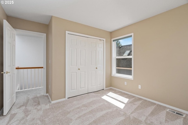 unfurnished bedroom with carpet floors, baseboards, a closet, and visible vents