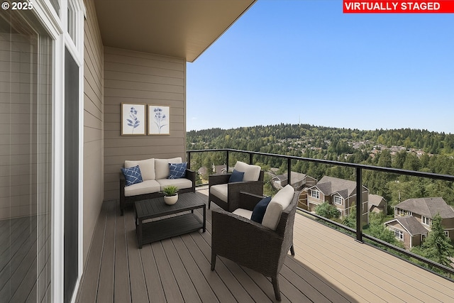 balcony with outdoor lounge area and a view of trees