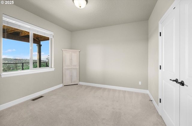 unfurnished room with light colored carpet and baseboards