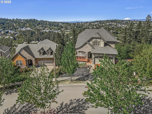 view of front of property featuring concrete driveway, stone siding, an attached garage, and roof with shingles