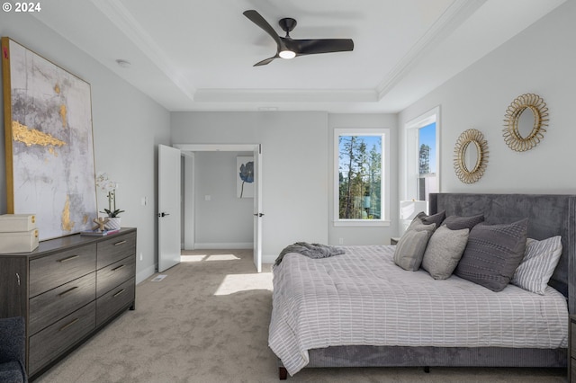 bedroom with baseboards, ornamental molding, a raised ceiling, and light colored carpet