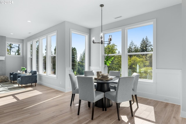 dining space featuring light wood-style floors, visible vents, a notable chandelier, and wainscoting