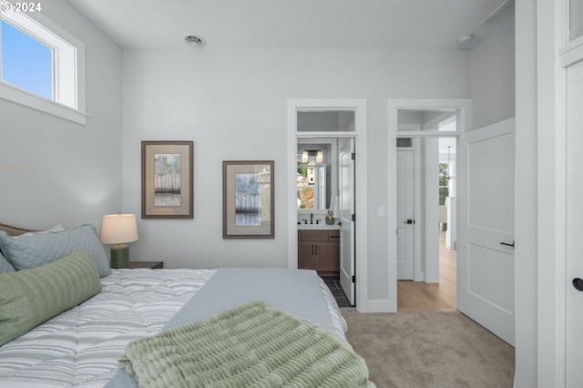 bedroom featuring multiple windows, a sink, visible vents, and light colored carpet