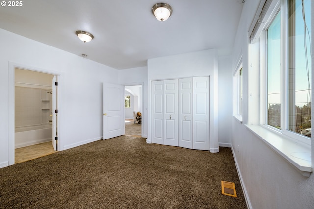 unfurnished bedroom with baseboards, carpet, a closet, and visible vents