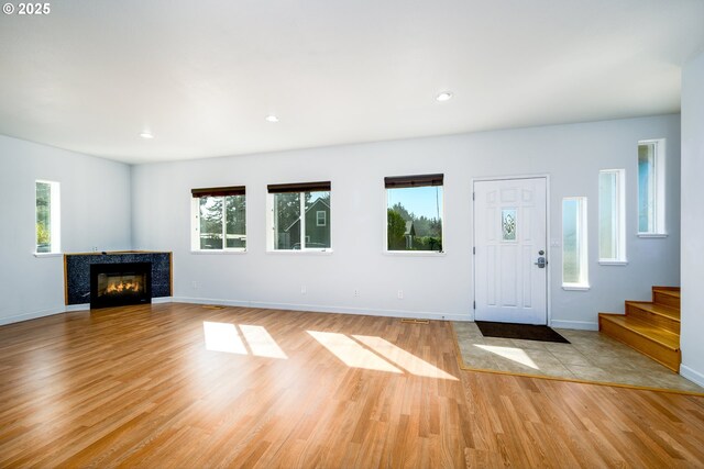entryway with stairs, a tile fireplace, light wood-style flooring, baseboards, and recessed lighting