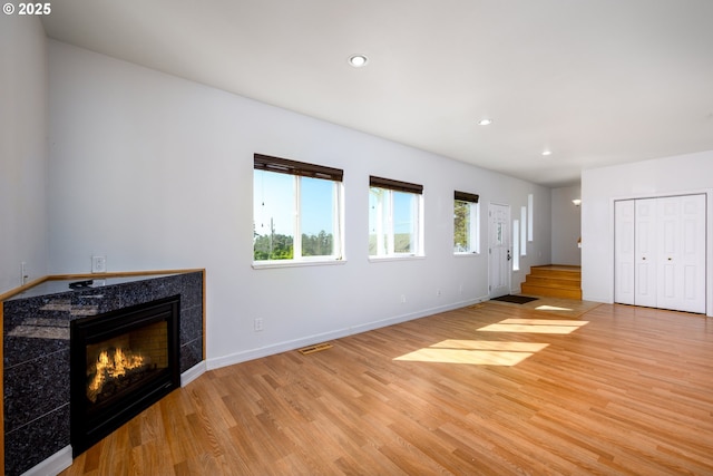 unfurnished living room featuring baseboards, visible vents, light wood-style floors, and a fireplace